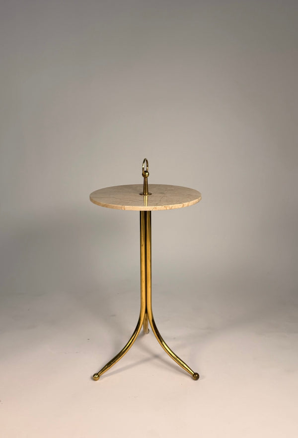 Small round table with marble top and brass base on a plain background