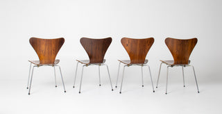 Four wooden chairs with metal legs on a white background