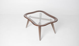 Close detail of Filippo Chissotti table showing chrome standoff hardware securing glass within sculpted walnut frame, postwar Italian design craftsmanship