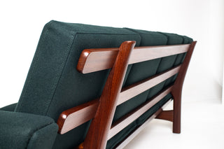 Angled rear view of restored Hans Wegner GE-236 four-seat sofa showing sculptural solid teak frame and signature slatted back construction.