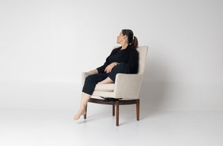 Woman sitting in a beige armchair on a white background