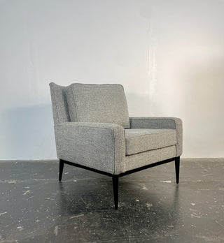 A gray upholstered Paul McCobb 312 Armchair with a black lacquer maple wood base and dark legs.