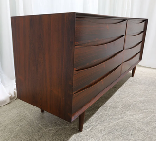 Wooden dresser with wavy design on a neutral background