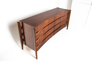 Wooden dresser with a curved design and exoskeletal legs on a white background
