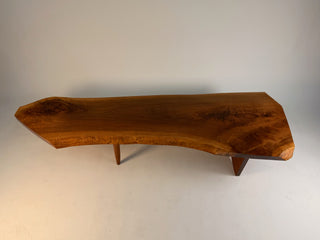 full view of George Nakashima conoid coffee table showing the gently sloped English walnut tabletop and rosewood butterfly joint. The natural live edges are visible along the back, supported by sculptural leg base beneath.