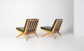 Two modern chairs with green cushions and wooden frames on a white background